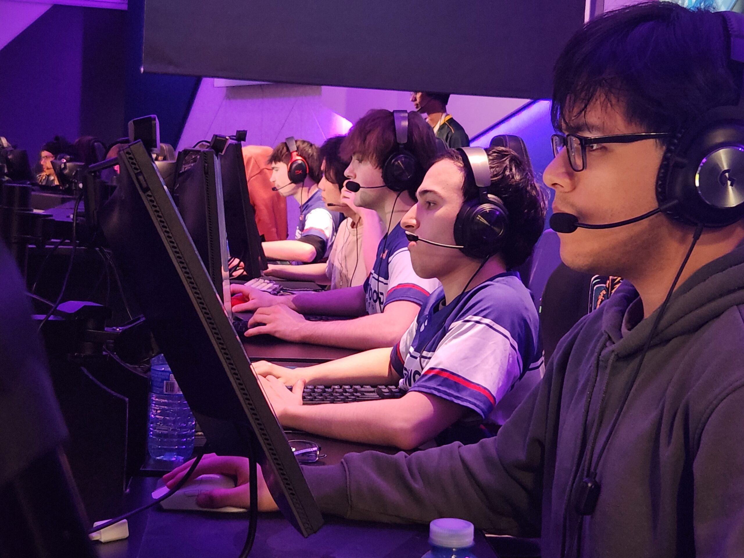 Professional esports players sitting in a row at their gaming setups during a tournament